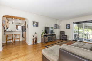 Living area with arched walkways, light wood-style floors, and recessed lighting