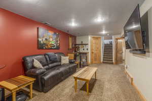 Living area with carpet flooring, stairway, a textured ceiling, and recessed lighting