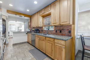 Kitchen with arched walkways, tasteful backsplash, recessed lighting, hanging light fixtures, and stainless steel dishwasher