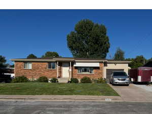 View of front of home with a front lawn, brick siding, and a garage