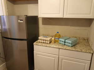 Kitchen featuring freestanding refrigerator and white cabinetry