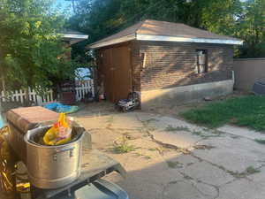 View of side of home featuring a patio area, brick siding, and an outdoor structure