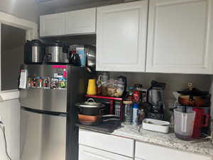 Kitchen with freestanding refrigerator, white cabinets, and light countertops
