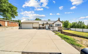 Ranch-style house with a garage, a chimney, stone siding, and concrete driveway