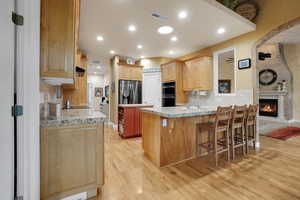 Kitchen featuring a kitchen bar, tasteful backsplash, light wood finished floors, a peninsula, and recessed lighting