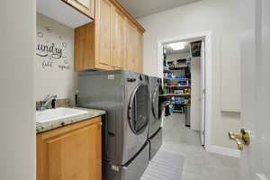 Washroom with washing machine and dryer, cabinet space, and light tile patterned flooring