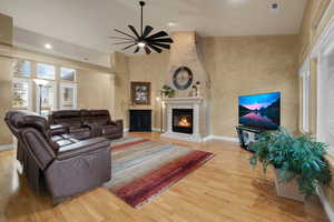 Living room featuring a glass covered fireplace, wood finished floors, a ceiling fan, and recessed lighting