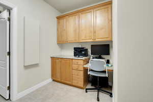 Office space featuring built in desk and light tile patterned floors