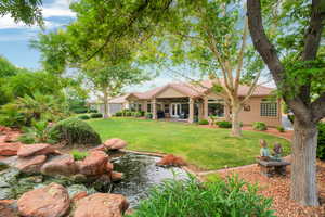 View of green lawn featuring a garden pond and an attached garage