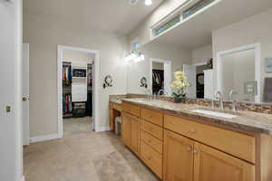 Full bath featuring double vanity, a walk in closet, and tile patterned flooring