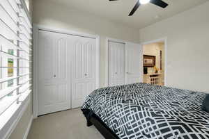Bedroom featuring two closets, light colored carpet, and a ceiling fan