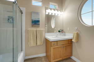 Full bathroom with tile patterned floors, vanity, and combined bath / shower with glass door