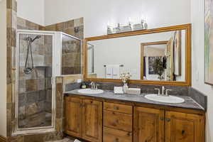 Full bathroom with double vanity and a shower stall