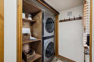 Laundry room with stacked washing machine and dryer and baseboards