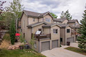 View of front of house with driveway, an attached garage, and roof with shingles