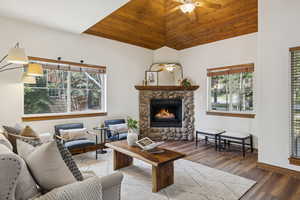 Living area with ceiling fan, vaulted ceiling, a fireplace, plenty of natural light, and wood finished floors