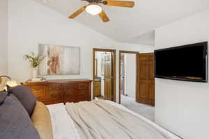 Bedroom featuring light colored carpet, ensuite bath, a ceiling fan, and high vaulted ceiling