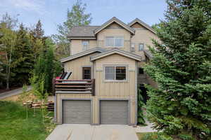 View of front of home featuring board and batten siding, driveway, a garage, a shingled roof, and a front lawn