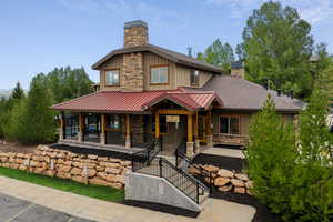 View of front of property featuring a chimney, covered porch, stone siding, and board and batten siding