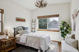 Bedroom with lofted ceiling, wood finished floors, and a chandelier