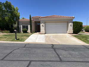 Mediterranean / spanish home with a garage, stucco siding, concrete driveway, a front yard, and a tile roof