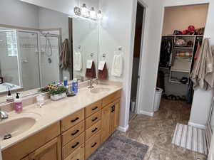 Bathroom featuring a stall shower, double vanity, and a walk in closet