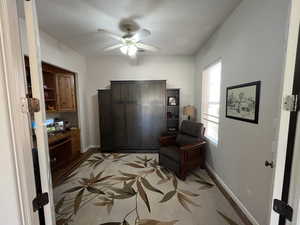 Sitting room featuring a ceiling fan and baseboards