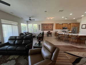 Living room with a ceiling fan, recessed lighting, light wood-type flooring, and a textured ceiling