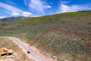 Aerial overview of property's location with property parcel outlined and a mountainous background