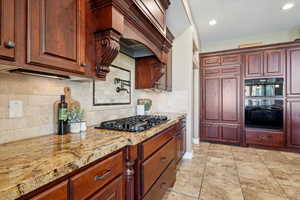 Kitchen featuring black appliances, light stone counters, tasteful backsplash, recessed lighting, and light tile patterned flooring