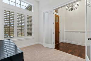 Unfurnished office with carpet, a decorative wall, hardwood / wood-style flooring, a chandelier, and a wainscoted wall