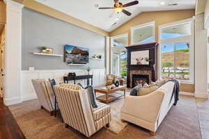 Living area with ceiling fan, a stone fireplace, decorative columns, recessed lighting, and wood finished floors