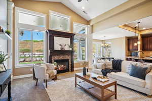 Living area with vaulted ceiling, a chandelier, light colored carpet, a fireplace, and recessed lighting