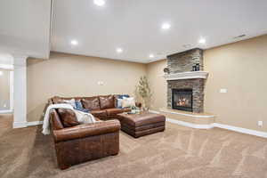 Living room featuring carpet, a stone fireplace, and recessed lighting