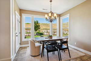 Dining area with a chandelier, plenty of natural light, and light stone finish flooring