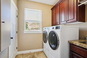 Washroom with cabinet space, washing machine and dryer, and light tile patterned floors