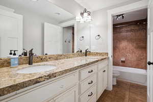 Full bathroom featuring double vanity, washtub / shower combination, and tile patterned flooring