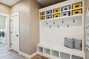 Mudroom with washing machine and dryer and light tile patterned floors