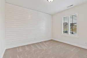 Spare room featuring light colored carpet and wood walls