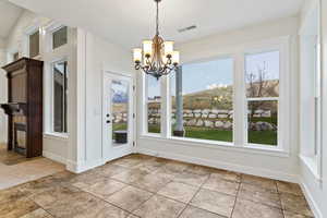 Unfurnished dining area featuring a chandelier and baseboards
