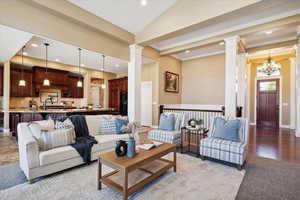 Living area featuring ornate columns, crown molding, recessed lighting, a chandelier, and lofted ceiling