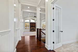 Hallway with vaulted ceiling, dark wood-style flooring, an upstairs landing, and ornamental molding