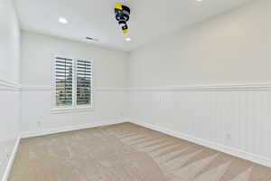 Unfurnished room with recessed lighting, carpet flooring, and a wainscoted wall
