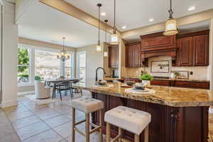 Kitchen featuring backsplash, a chandelier, light tile patterned floors, a breakfast bar area, and recessed lighting