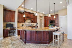 Kitchen featuring backsplash, recessed lighting, pendant lighting, a breakfast bar area, and a large island with sink