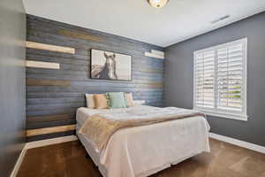 Bedroom with wood walls, an accent wall, and carpet