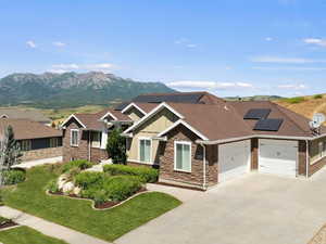 Craftsman-style home with board and batten siding, a garage, concrete driveway, a front lawn, and roof mounted solar panels