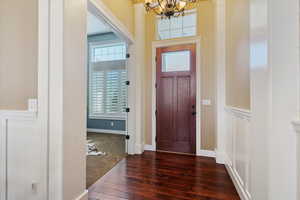 Foyer with a chandelier, hardwood / wood-style floors, and wainscoting