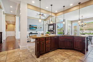Kitchen featuring pendant lighting, stone countertops, recessed lighting, a center island with sink, and a chandelier
