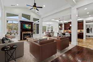 Living room featuring light wood-style flooring, a chandelier, a ceiling fan, recessed lighting, and a glass covered fireplace